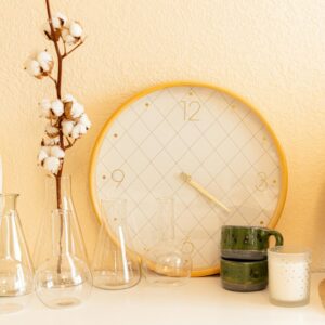 Stylish home interior featuring a decorative clock, cotton flowers, and glassware on a cabinet.