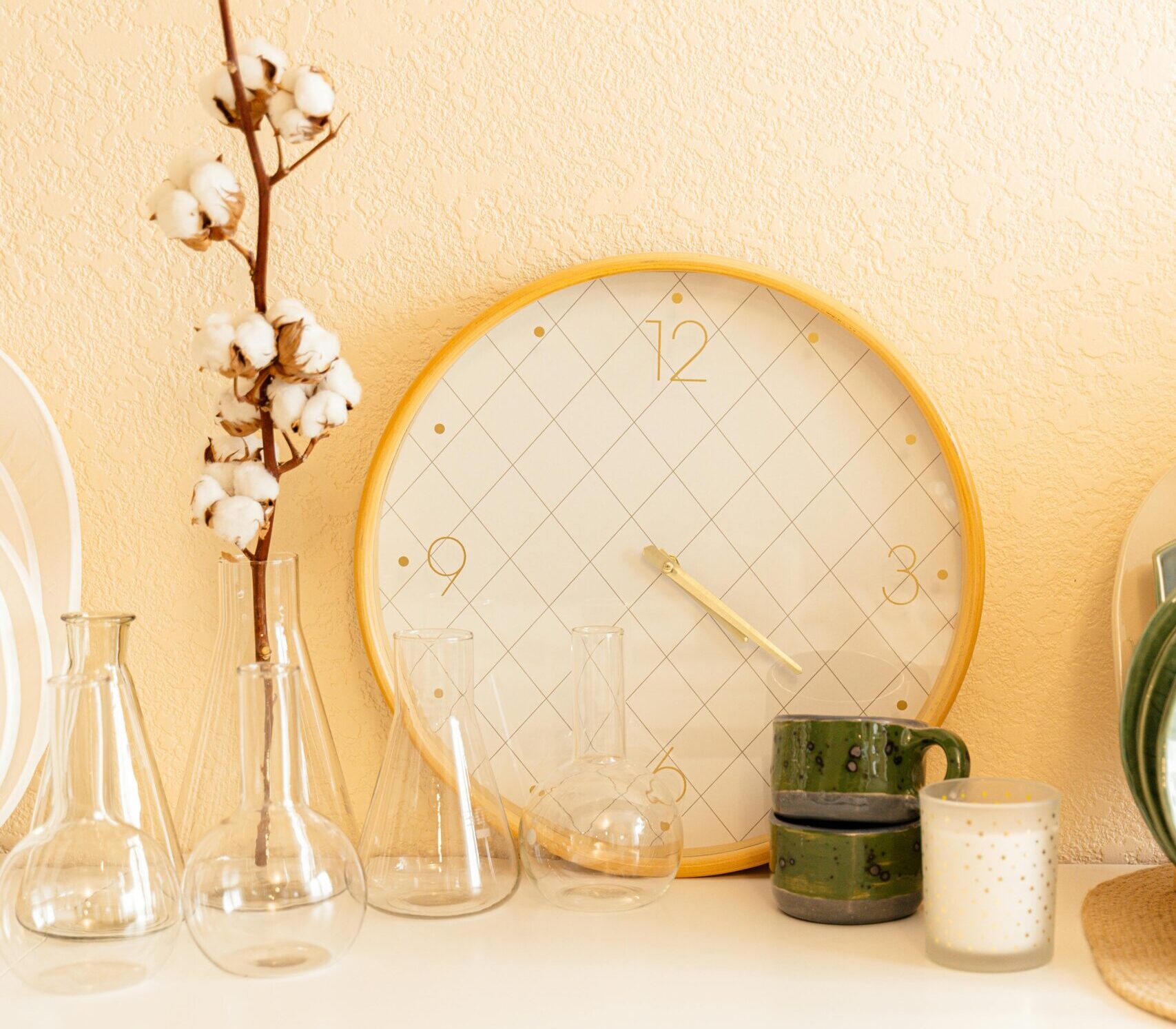 pexels photo 6694685 6694685 Stylish home interior featuring a decorative clock, cotton flowers, and glassware on a cabinet.
